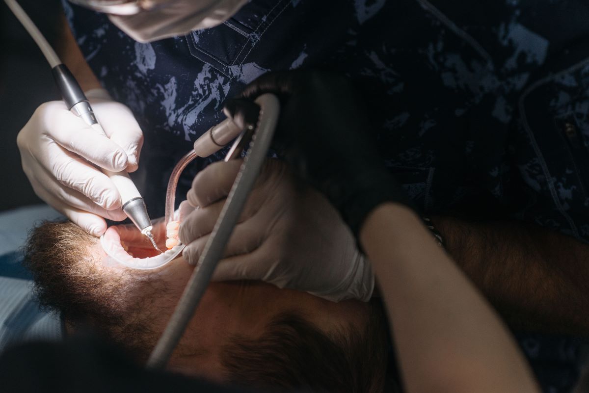 Scaling and Root Planing at Aroma Dental in Humble, TX: a hygienist performing deep scaling and root planing below the gum line for a periodontal patient