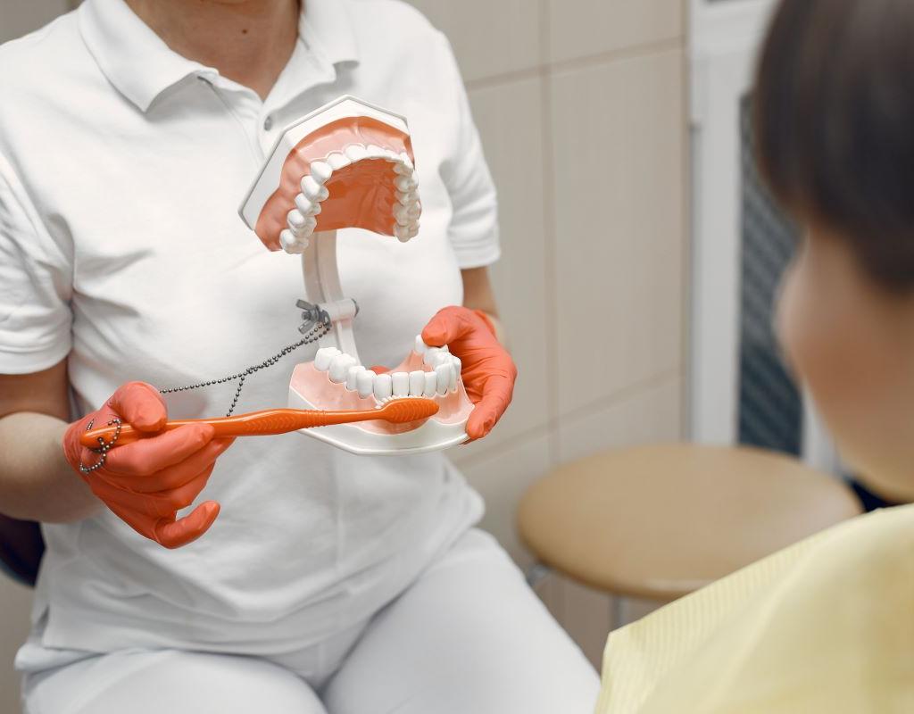 Dental Hygiene at Aroma Dental in Humble, TX: a dental hygienist coaching a patient on brushing and flossing technique at the chair
