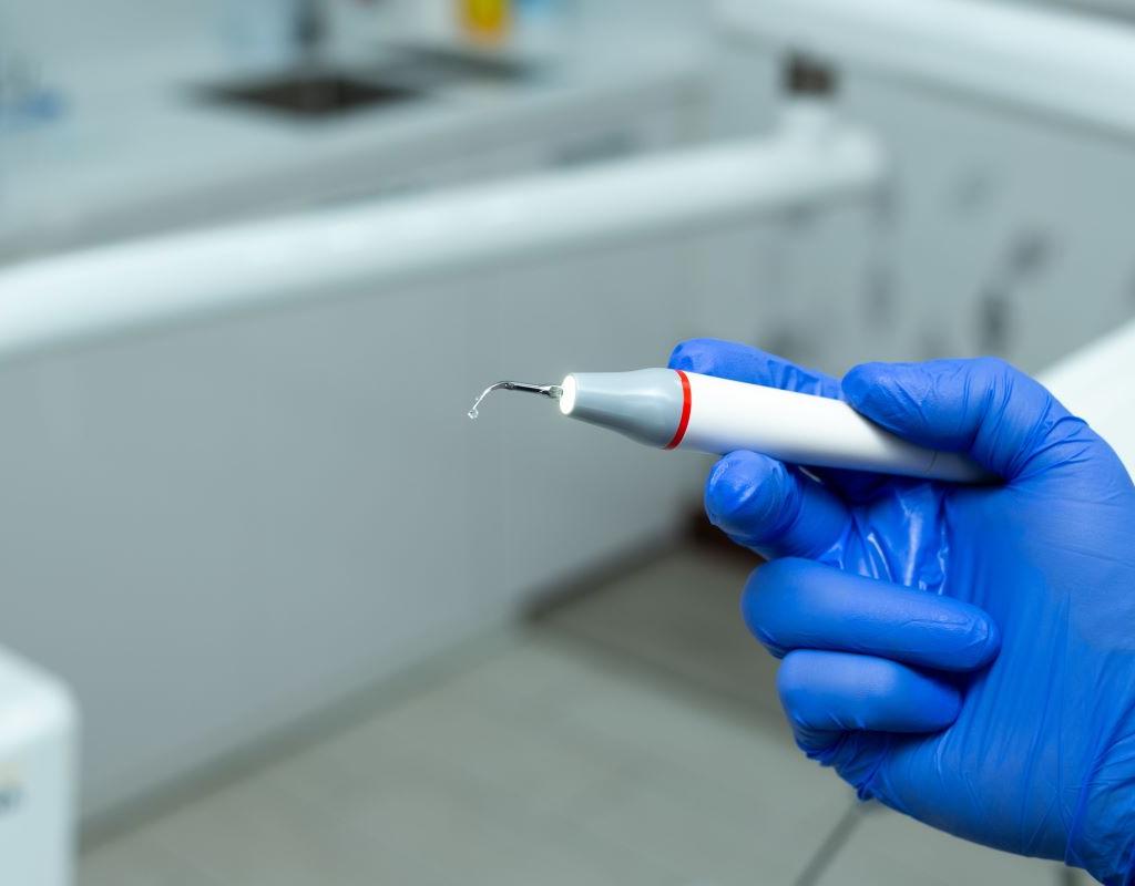 Scaling and Root Planing at Aroma Dental in Humble, TX: a hygienist performing deep scaling and root planing below the gum line for a periodontal patient